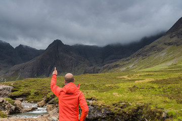 Fototapeta na wymiar Man looking at the Fairy Pools waterfalls, isle of Skye, Scotland