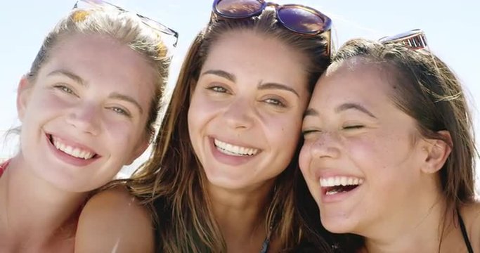 Close up portrait of three teenage girl friends smiling on tropical beach slow motion
