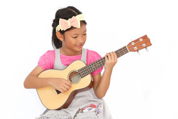 Little asian girls sing a song and playing ukulele isolate on wh