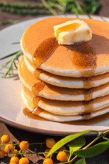 Stack of delicous pancake topped with butter and maple syrup