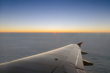 Wing of airplane and sunset sky