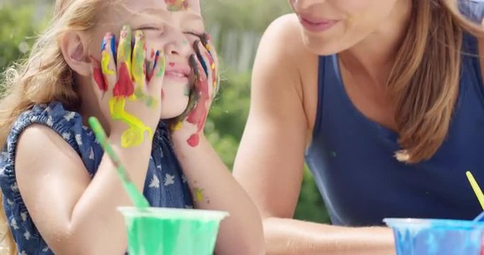 Happy family  with little girl painting in the yard
