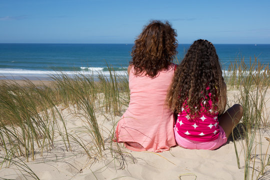Back view of two girls on holidays at the beach