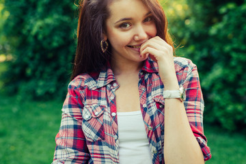 Fototapeta premium Brown hair girl sitting on the grass in the park and posing to the photo.