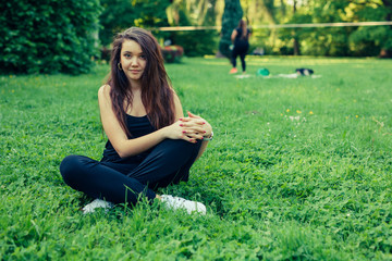 Fototapeta premium Brown hair girl sitting on the grass in the park and posing to the picture.