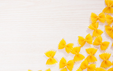 Uncooked pasta farfalle on a wooden board