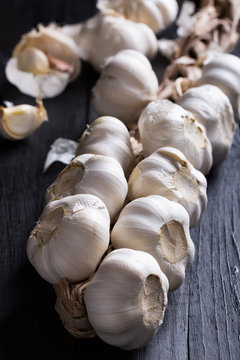 plait of white garlic on black wooden background