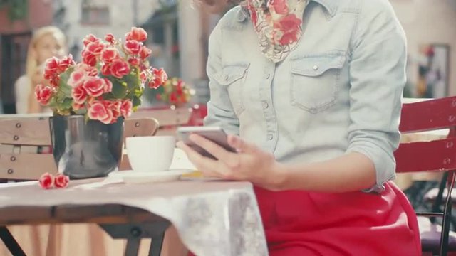 Young Girl is Using Mobile Phone in Outdoor Coffee Shop