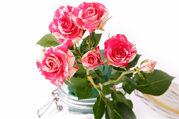bouquet of roses in a glass jar on a white background