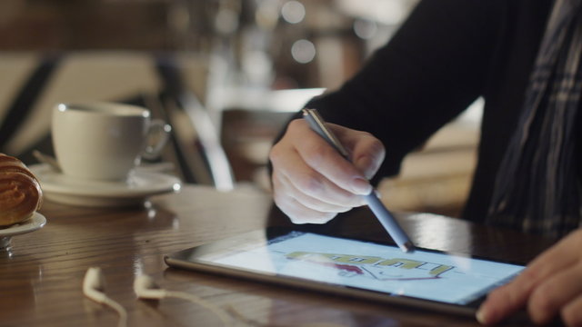 Woman Drawing on Tablet PC in Coffee Shop. 