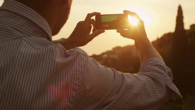 Man Taking Photos of Nature with a Phone at Sunset Time
