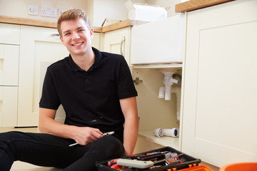 Apprentice plumber sitting in a kitchen, portrait