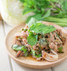 Thai cuisine spicy pork salad on wood table