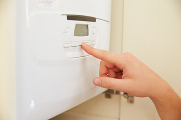 Hand of person using domestic boiler controls, close up