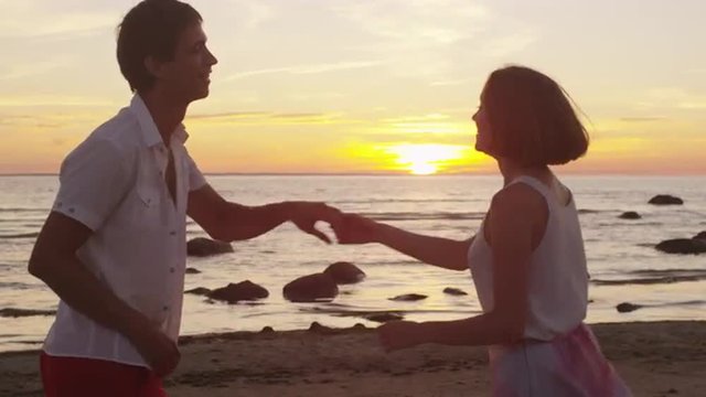 Couple is Dancing on the Beach in Sunset Time.