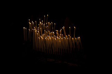 Candles in Church. In Europe, people light candles inside the churches . The candles are lit with a prayer, usually to remember someone or to help with an issue. - obrazy, fototapety, plakaty