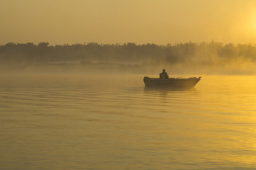 Wędkarz na łodzi łowiący w mglisty poranek nad rzeką © Mike Mareen