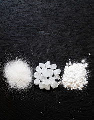 Sugar, candy sugar, white sugar powder on dark stone background,
