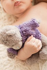 Beautiful innocent newborn sleeping. Adorable little girl holding close to him his bear toy