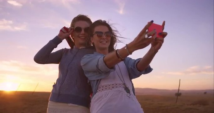 beautiful Girl friends taking selfies on road trip at sunset with vintage car