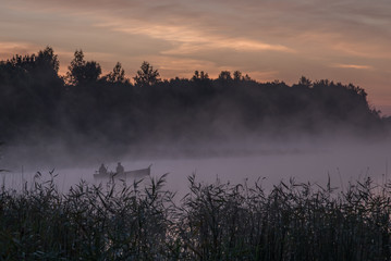 Anonymous fishermen in the morning fog on a lake