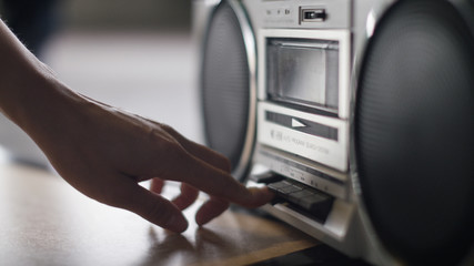 Close up of female hand pressing play on a retro stereo cassette player