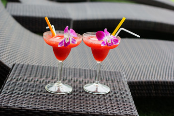 Two cocktails with strawberry and orchid flower