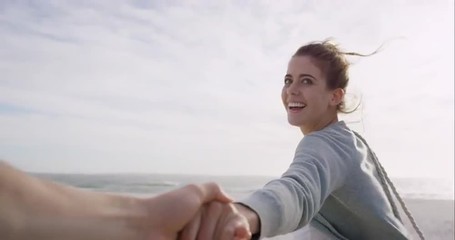 POV of Young couple holding hands woman leading boyfriends walking towards sunset on empty beach - Powered by Adobe