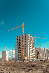 Fototapeta na wymiar Tall cranes and modern buildings under construction