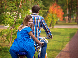 Fototapeta premium Smiling girl riding on a tandem bike and turned around