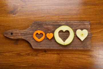 Fruits slices with cut in shape of heart on wooden background