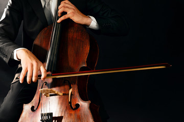 Man playing on cello on dark background