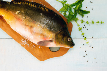 Raw fish (tenchе) with basil on a wooden cutting board, top vie