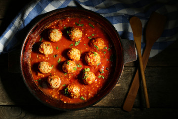 Pan with meat balls in tomato sauce, on wooden background