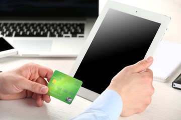Man holding credit card and tablet on workplace background