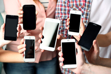 Many hands holding mobile phones close up