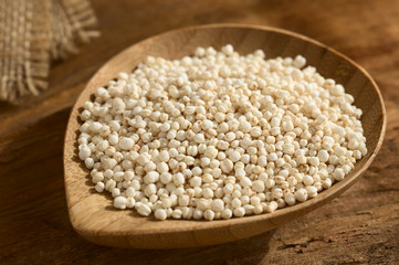 Popped white quinoa (lat. Chenopodium quinoa) cereal on small wooden plate, photographed on wood with natural light (Selective Focus, Focus one third into the quinoa cereal)