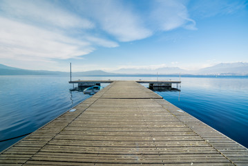 Wooden jetty, blue sky over horizon with daylight at Viverone Lake, Italy © OkFoto.it