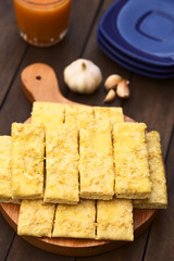 Fresh homemade garlic and cheese sticks made of a yeast dough served on wooden board (Selective Focus, Focus one third into the garlic sticks)