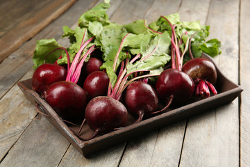 Young beets with leaves on wooden table close up