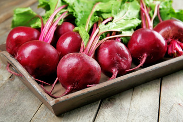 Young beets with leaves on wooden table close up