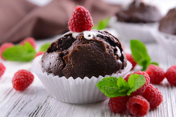 Delicious chocolate cupcake with berries on wooden table close up