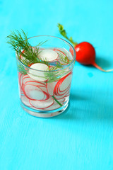 Glasses of cold refreshing summer drink with radishes and ice cubes on table close up