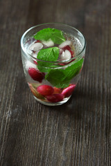 Glass of cold refreshing summer drink with berries and ice cubes on table close up