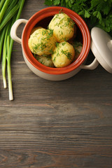 Boiled potatoes with dill in pan on table close up