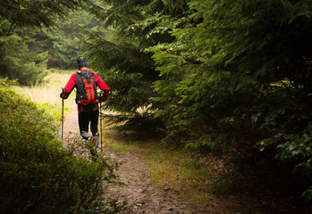 man with backpack and poles training ultra trail in the mountains
