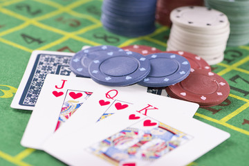 Close up of cards with poker chips on green carpet