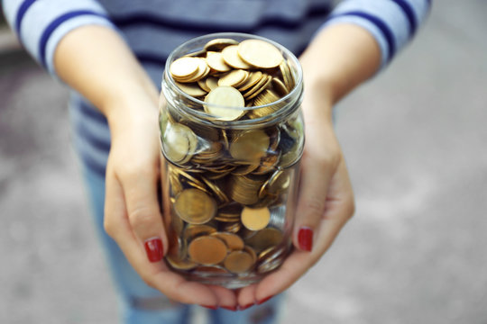 Woman Holding Money Jar With Coins Outdoors