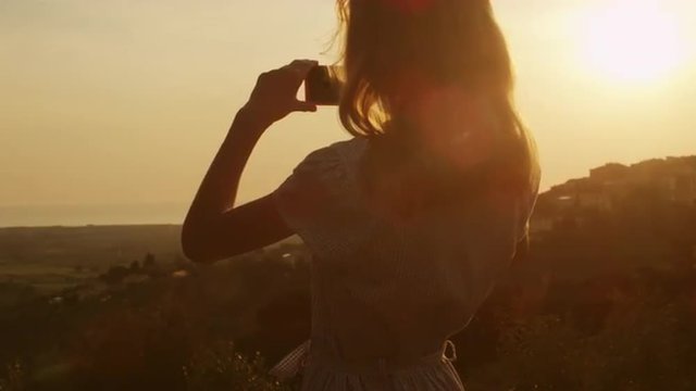 Girl Taking Photos of Nature with a Phone at Sunset Time