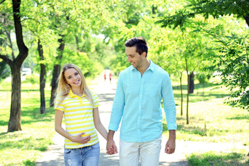 Young pregnant woman with husband in park